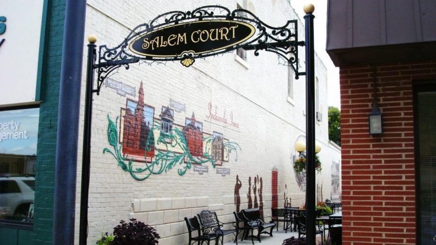 The Salem Court entrance sign, mural, and seating in an alley off Indianola's downtown square.